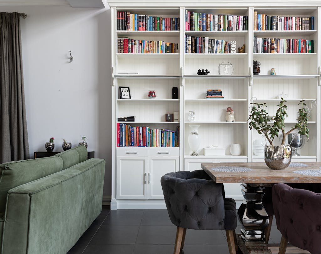 Elegant modern living room with bookcase, plush sofa, and decorative plants.