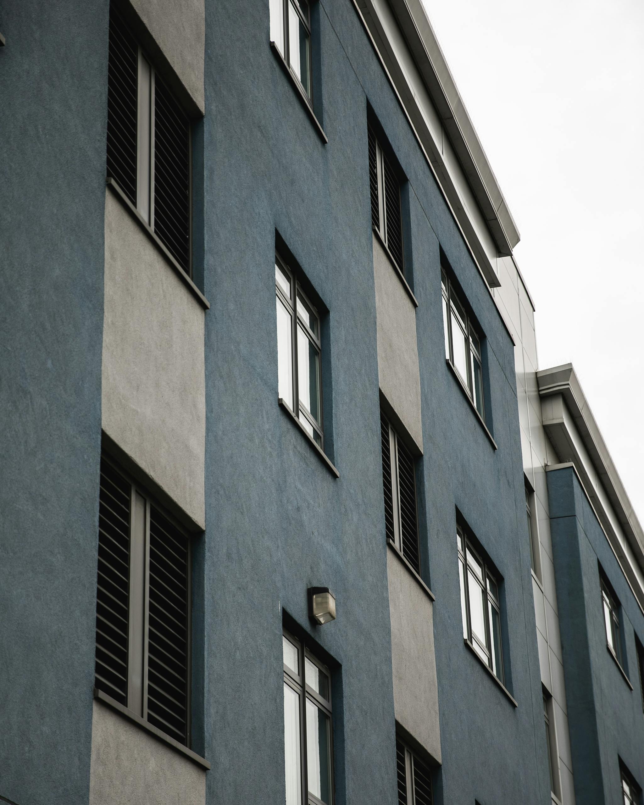 Modern apartment building facade showcasing blue and gray exterior with windows.