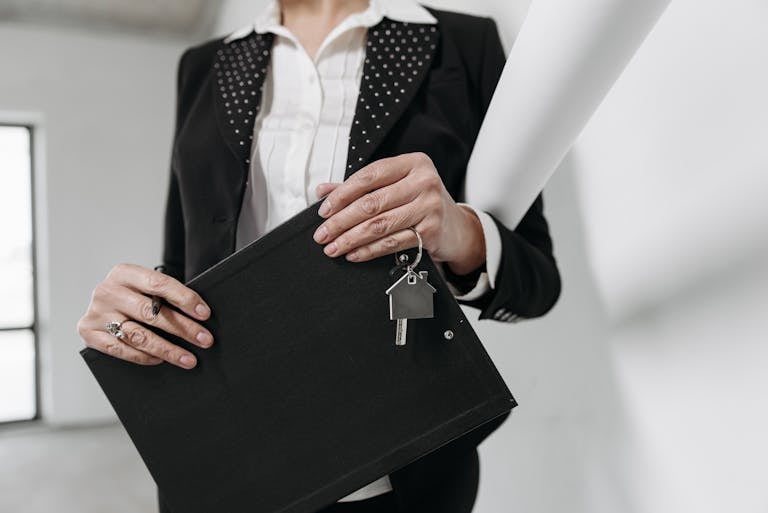 Close-up of a realtor holding a keychain and clipboard with interior office background.