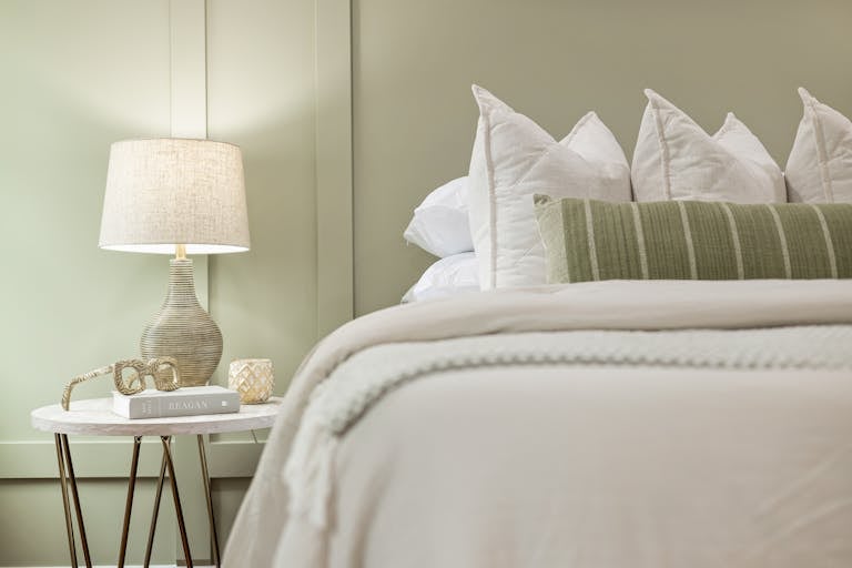 Elegant bedroom scene featuring a modern lamp, plush pillows, and soft bedding for a serene ambiance.