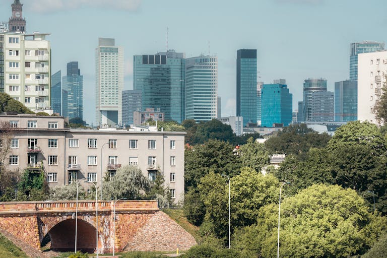 Stunning Warsaw skyline with modern skyscrapers and lush park in the foreground.