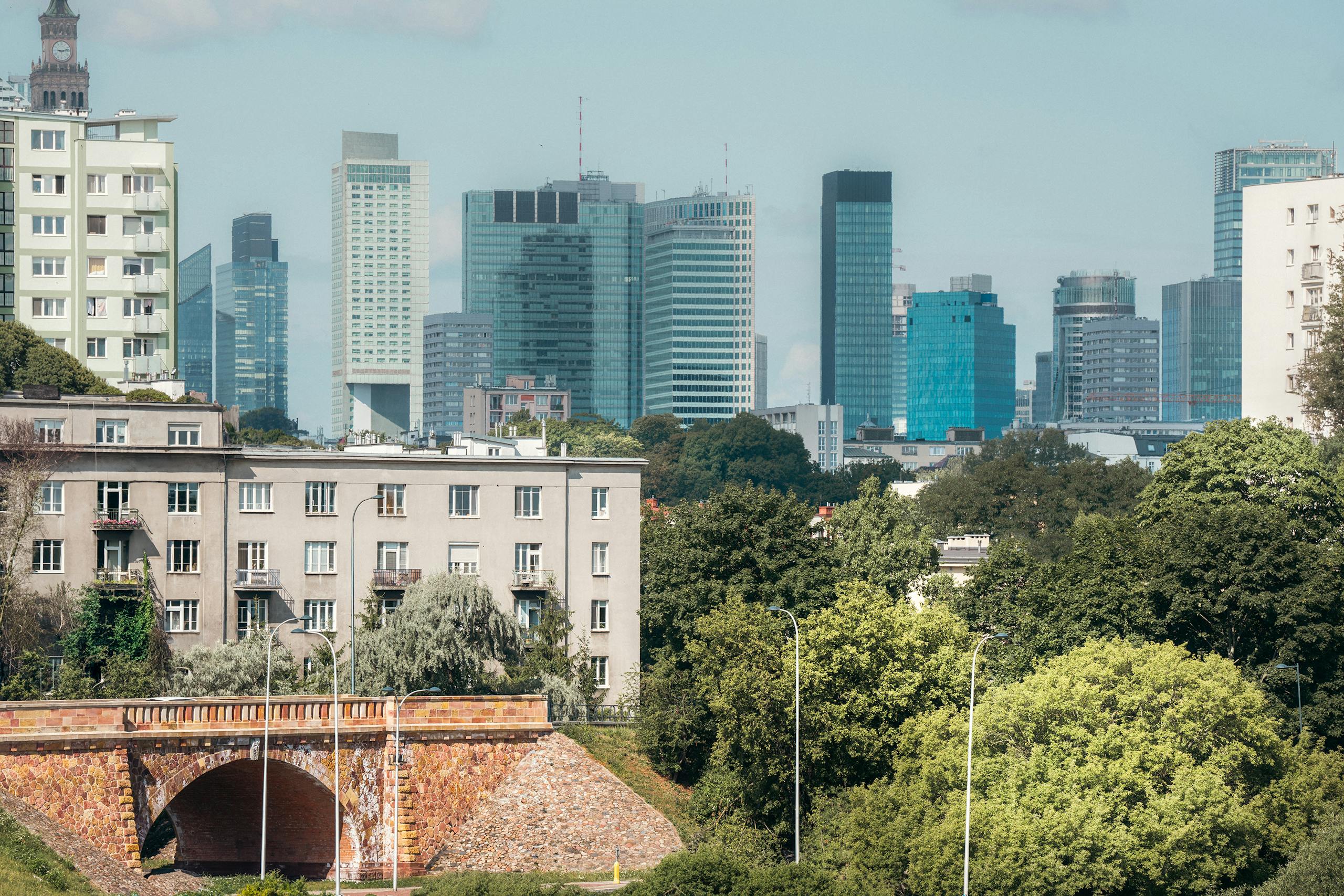 Stunning Warsaw skyline with modern skyscrapers and lush park in the foreground.