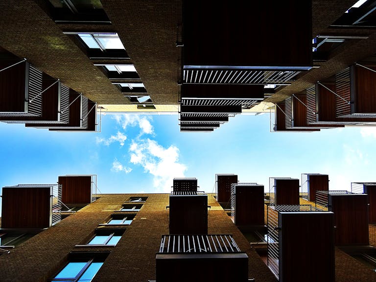 Low-angle view of modern architecture buildings with balconies, showcasing vibrant sky and clouds.