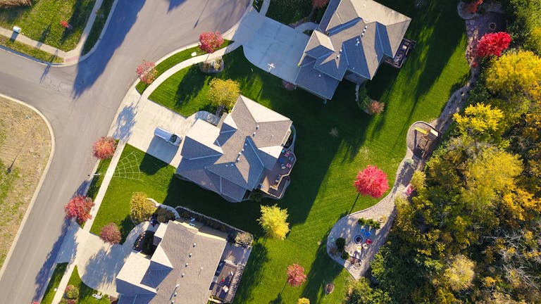 A picturesque aerial view showcasing suburban homes with vibrant gardens and tree-lined streets.