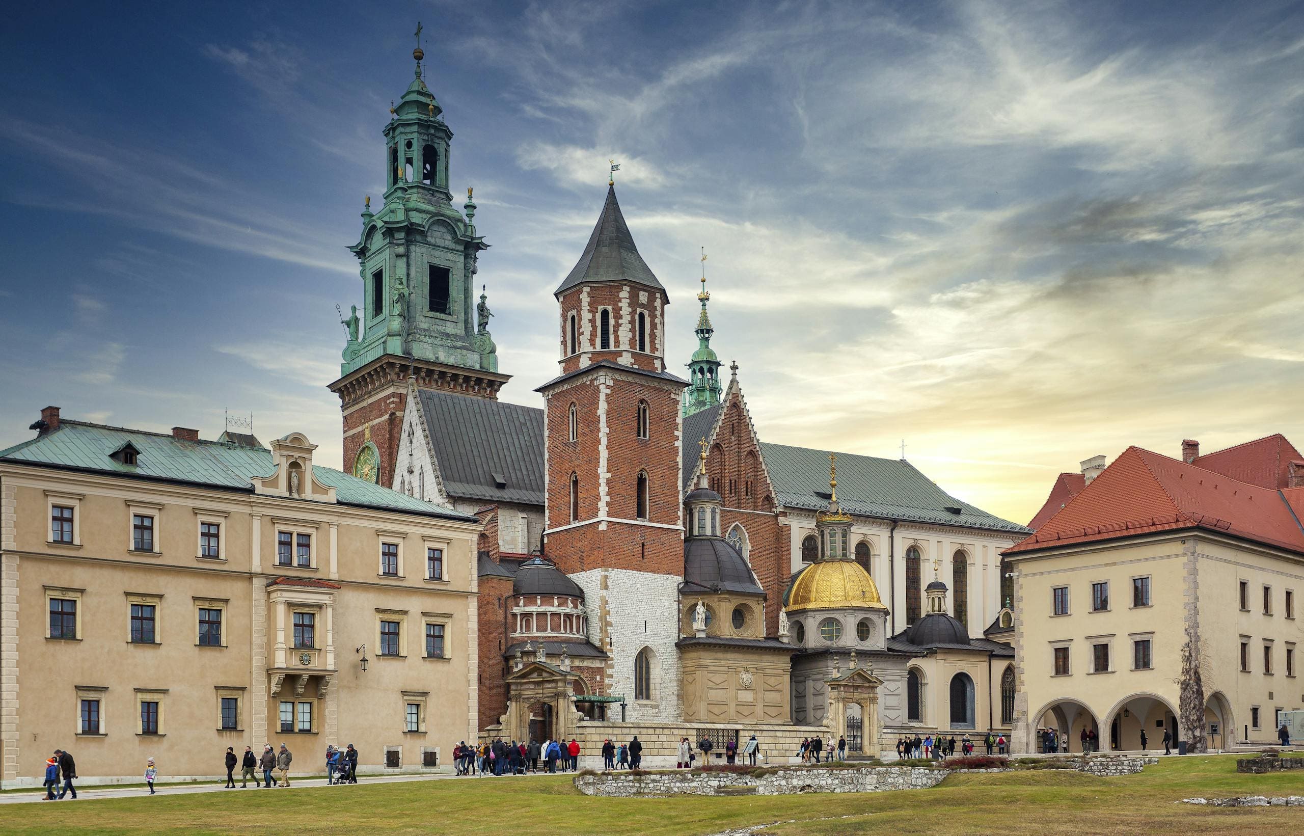 Zabytkowe budynki i starożytna katedra wawelska z wieżami na wzgórzu w Krakowie pod pochmurnym niebem