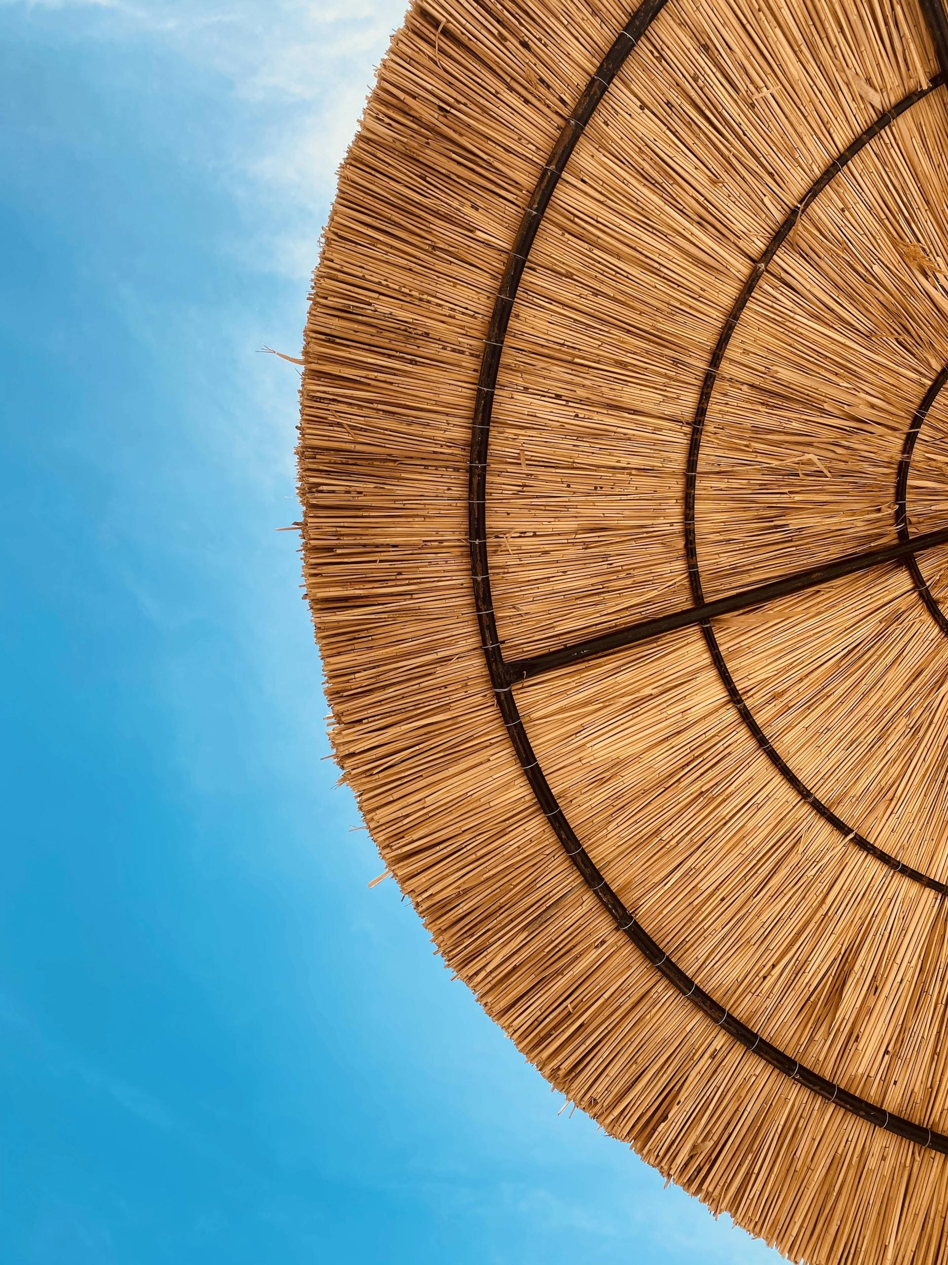 Naturalny parasol ze słomy na plaży pod jasnym błękitnym niebem tworzący wakacyjny nastrój