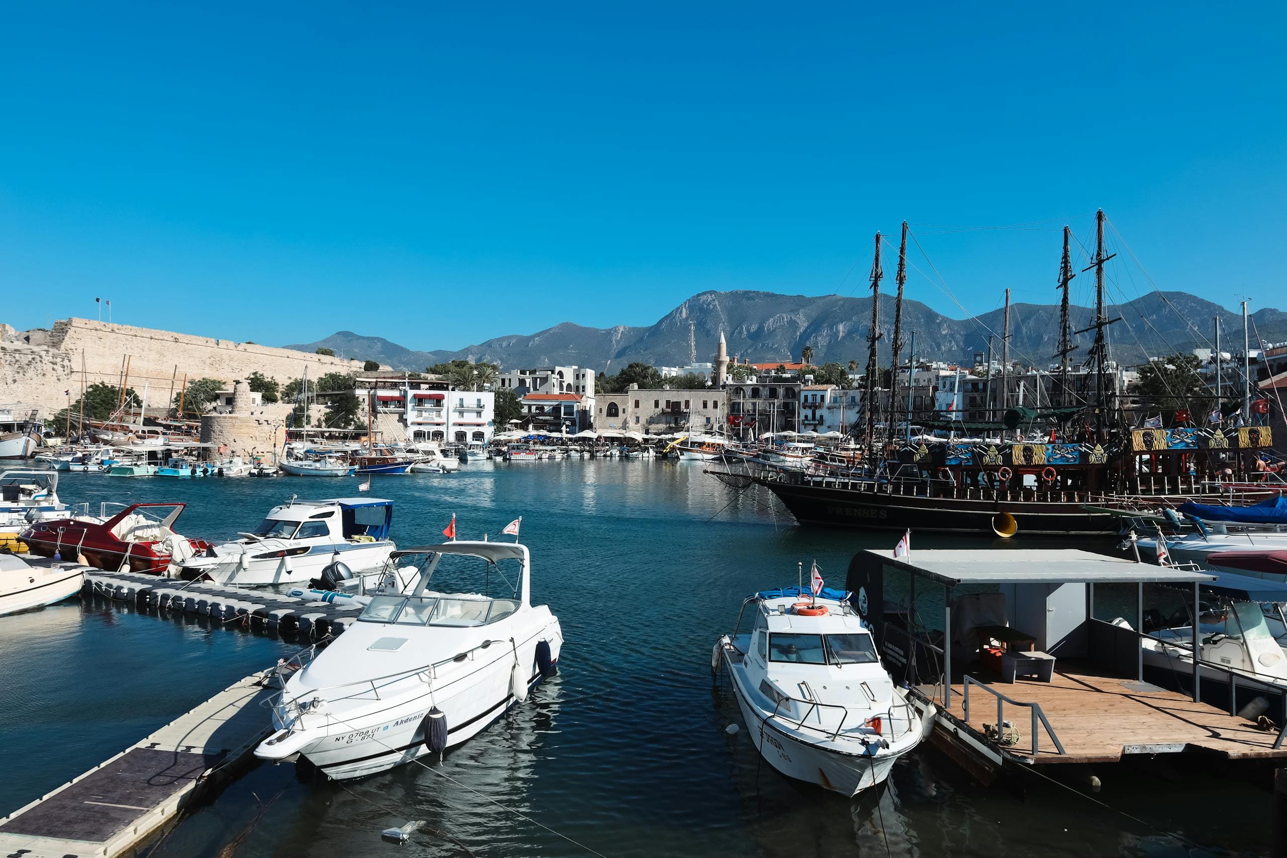 Malownicze jachty cumujące w porcie w Kyrenii na Cyprze z górami w tle i spokojną wodą