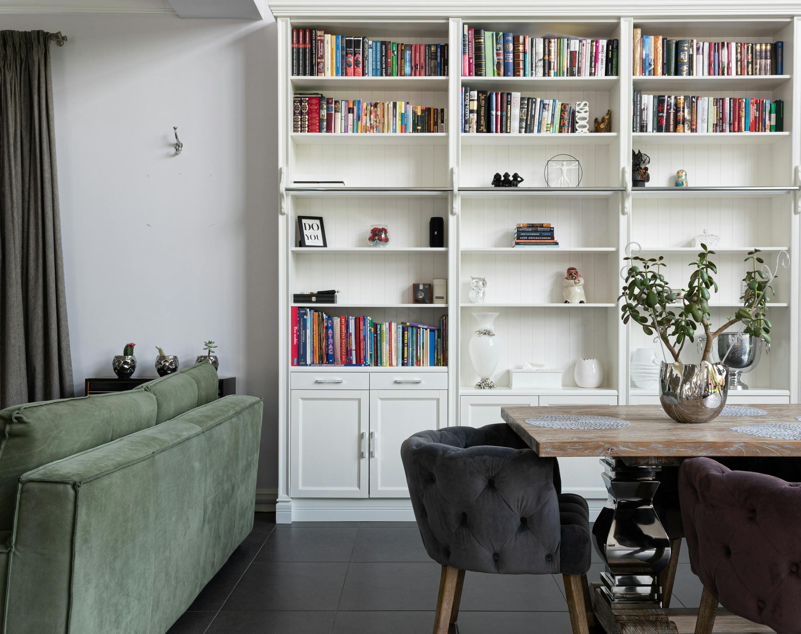 Stylowy salon z biblioteczką, pluszową sofą i ozdobnymi roślinami w nowoczesnym wnętrzu