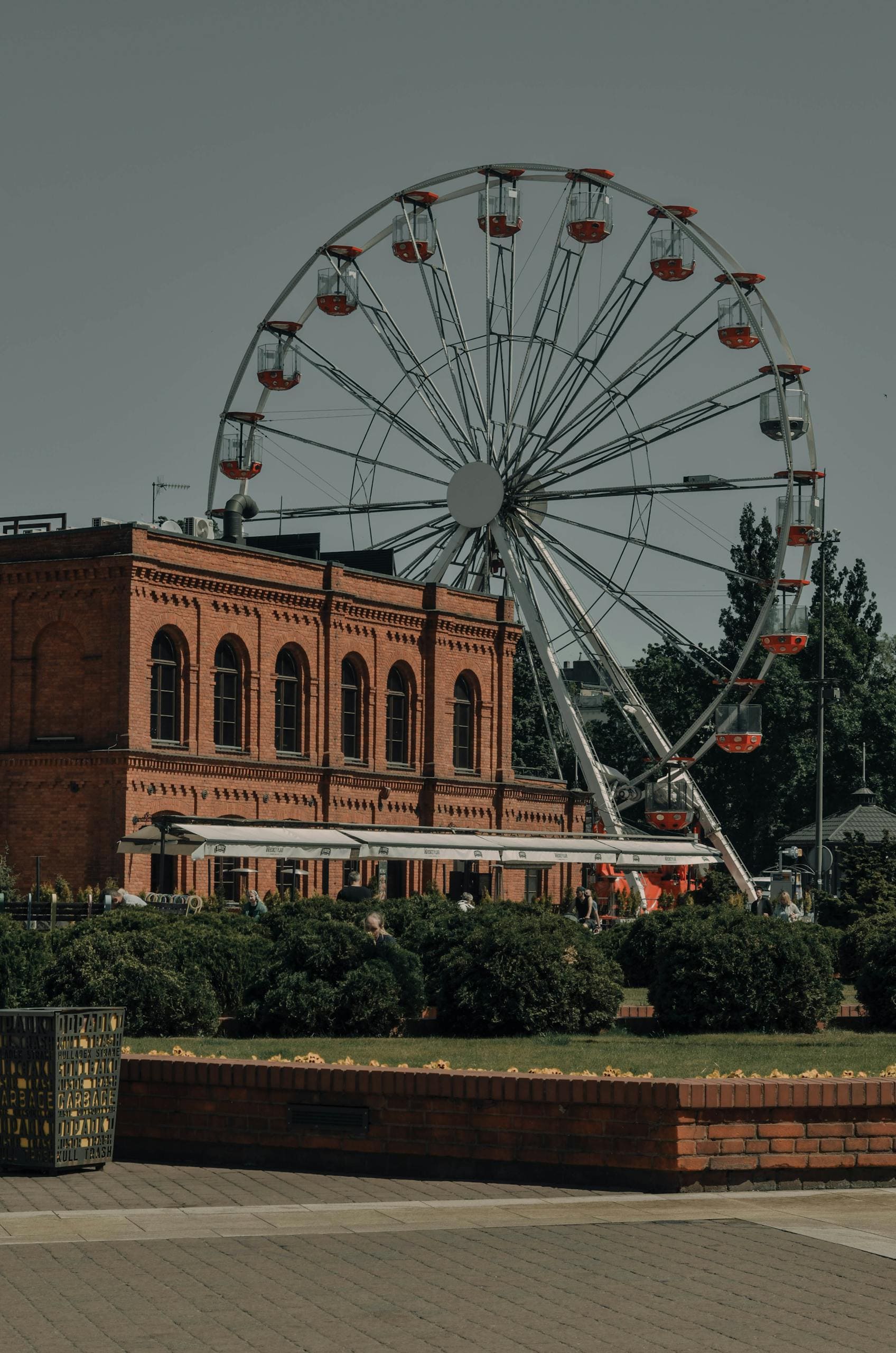 Kolorowy diabelski młyn obok historycznego budynku z cegły w centrum miasta Łódź.