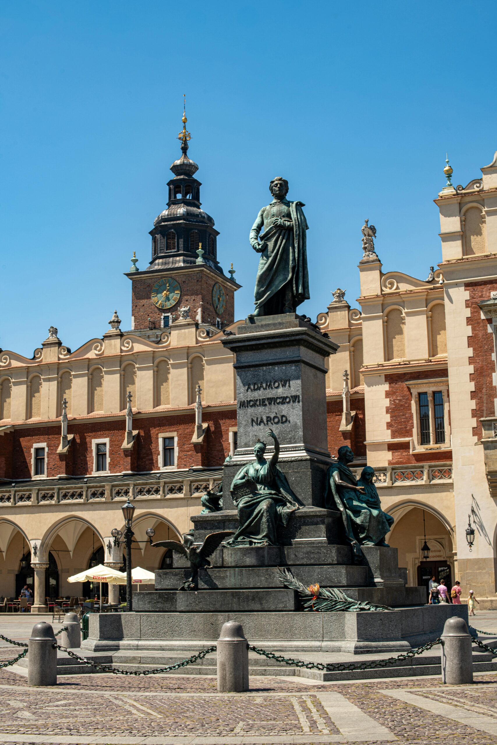 Pomnik Adama Mickiewicza na krakowskim Rynku Głównym z Sukiennicami i Wieżą Ratuszową w tle. Symbol polskiej literatury w sercu Starego Miasta Krakowa - główna atrakcja turystyczna i miejsce spotkań.