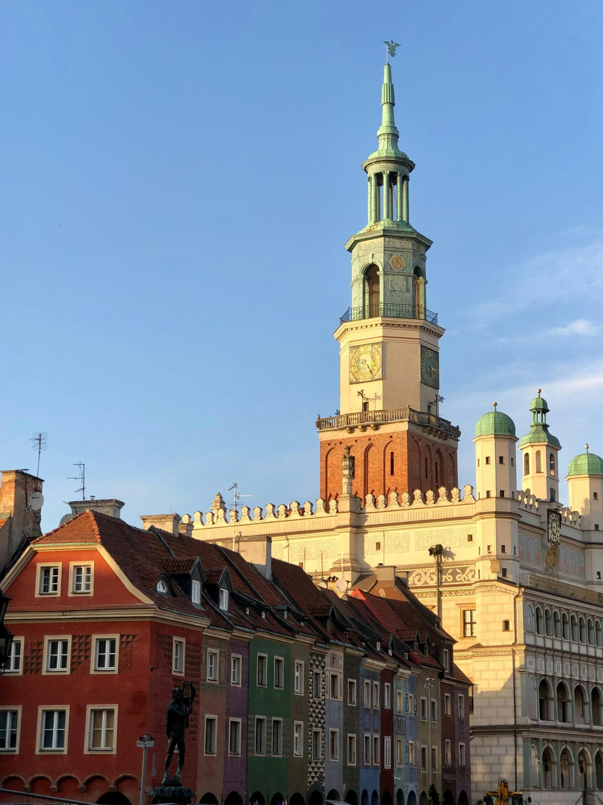 Renesansowy Ratusz w Poznaniu z charakterystyczną wieżą zegarową na Starym Rynku. Kolorowe kamieniczki u podnóża zabytkowego ratusza - symbol miasta i główna atrakcja turystyczna Poznania.