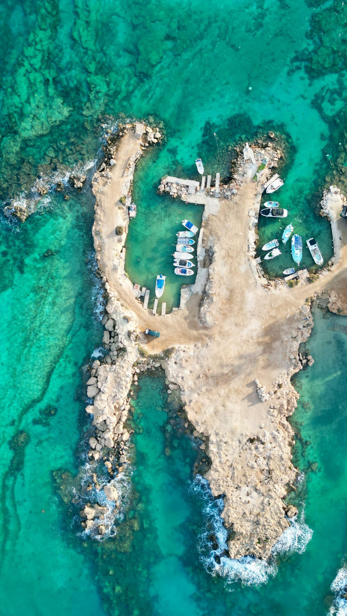 Protaras Cypr z drona - mała przystań rybacka z łódkami w krystalicznie czystej turkusowej wodzie, widok z lotu ptaka na zatokę Morza Śródziemnego