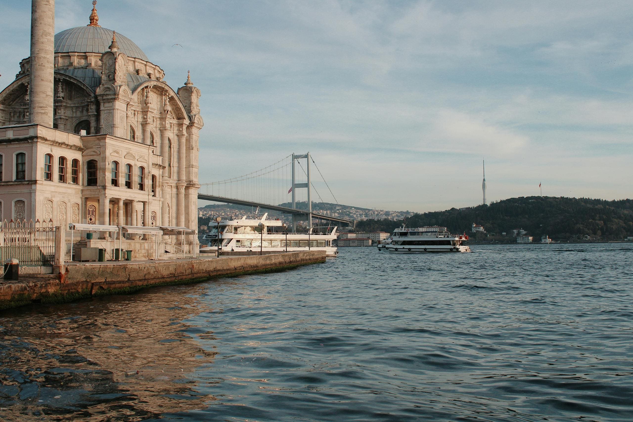 Meczet Ortaköy Istambuł z mostem Bosforu - barokowy meczet nad cieśniną Bosfor, 15 Temmuz Şehitler Köprüsü w tle, łódki pasażerskie i architektura osmańska Turcji