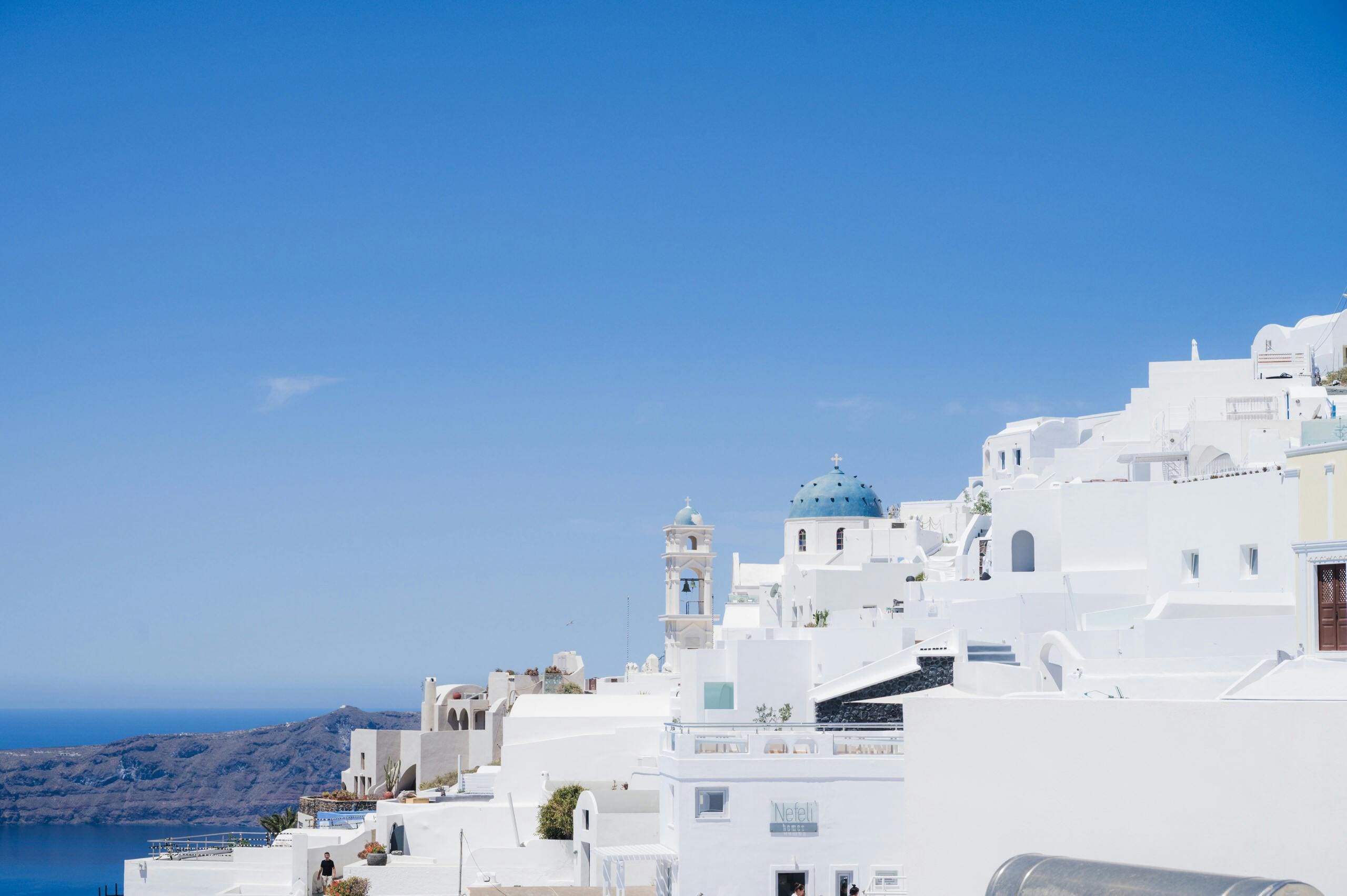 Santorini białe domy architektura - tradycyjna grecka wioska z niebieskimi kopułami nad Morzem Egejskim z dzwonnicą i tarasową zabudową