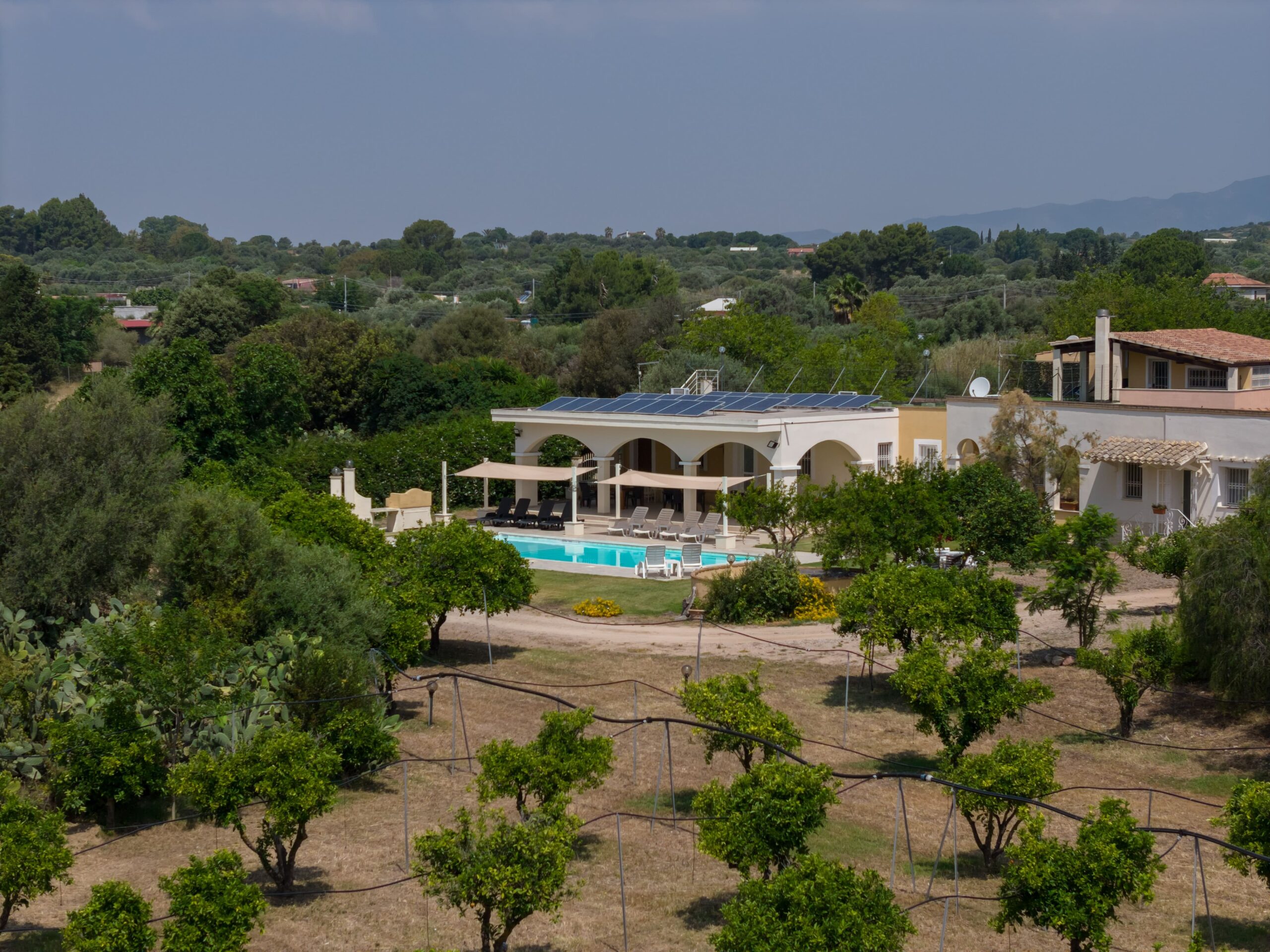 Willa z basenem Sardynia z drona - luksusowa nieruchomość z arkadami i panelami solarnymi w gaju oliwnym, śródziemnomorska villa w krajobrazie wzgórz Sardynii, ekskluzywna rezydencja z ogrodem