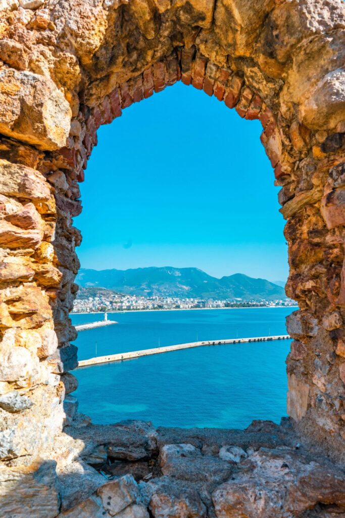 Turcja Alanya widok przez okno zamku - panorama miasta i portu przez historyczne kamienne okno twierdzy, spektakularny widok na Morze Śródziemne z góry zamkowej, nieruchomości z widokiem na zatokę program obywatelstwa tureckiego