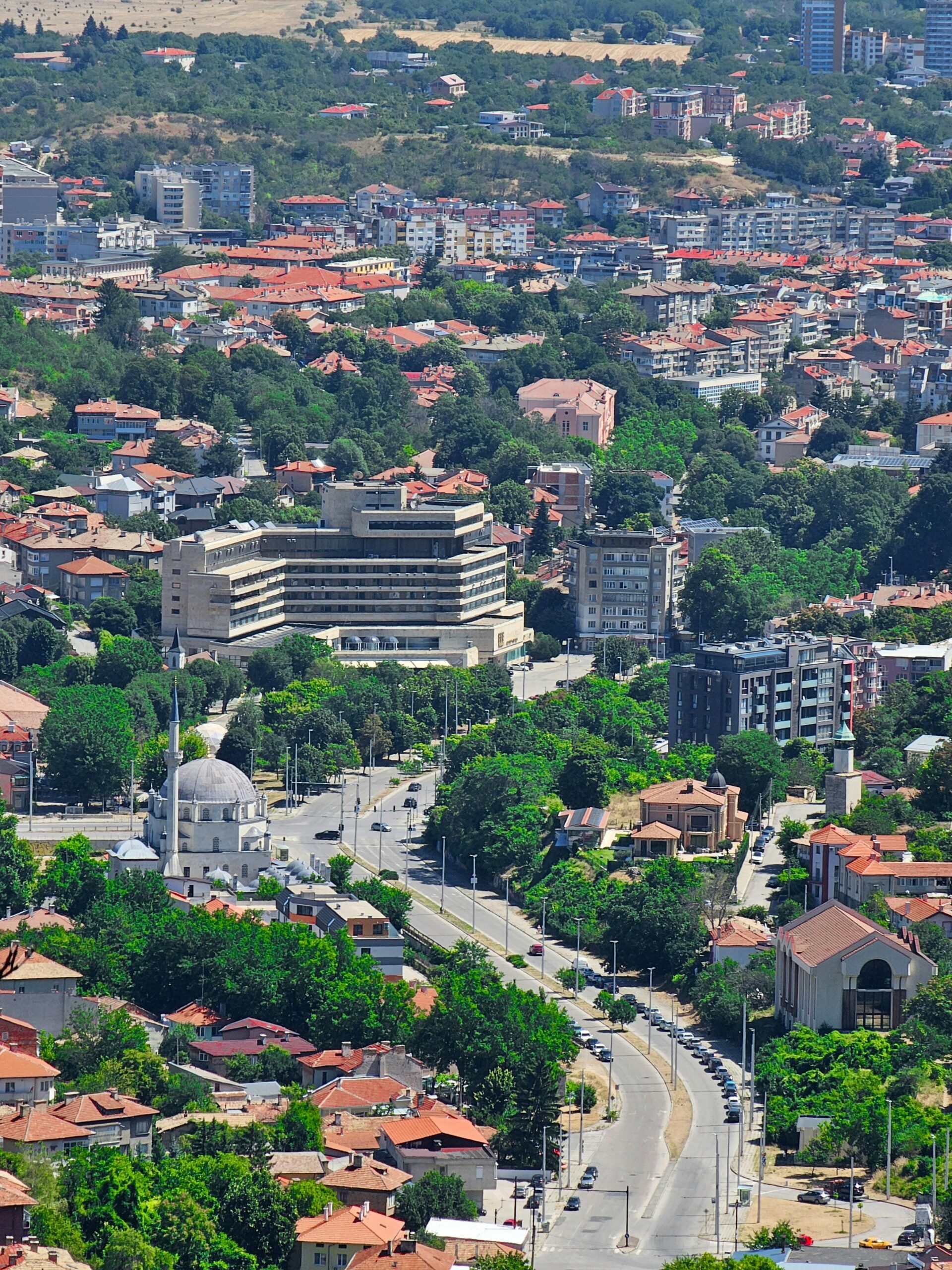 Bułgaria panorama miasta z lotu ptaka - mieszana architektura tradycyjne czerwone dachy i nowoczesne apartamentowce, centrum miasta z meczetem i zielenią miejską, nieruchomości w rozwiniętym mieście