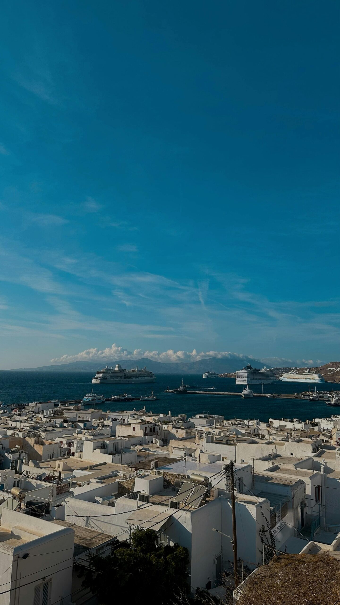 Panorama białej zabudowy Mykonos Town z widokiem na port i statki wycieczkowe na Morzu Egejskim, Cyklady Grecja