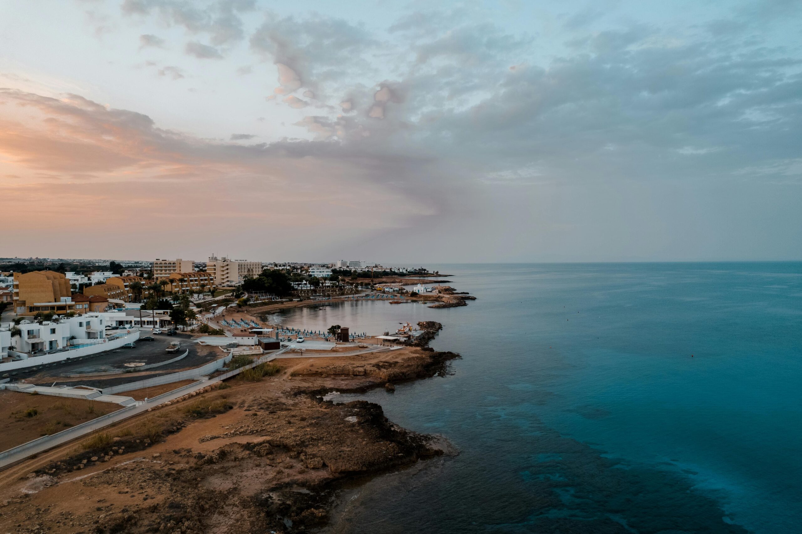 Linia brzegowa Protaras o zachodzie słońca – plaże i zabudowa hotelowa nad turkusowym Morzem Śródziemnym, Cypr