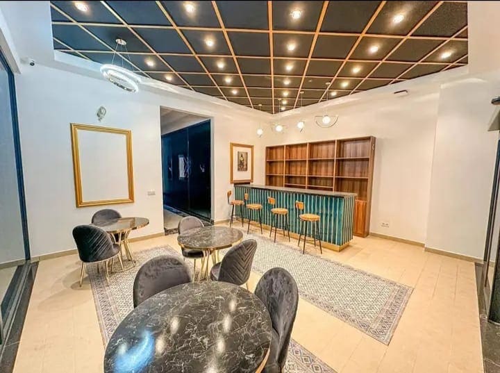 Luksusowe wnętrze apartamentowca, strefa wspólna, concierge - nowoczesna strefa wypoczynku z turkusową wyspą recepcja i marmurowymi blatami, ekskluzywne mieszkanie z designerskim oświetleniem sufitowym, high-end interior z przestrzenią do spotkań
