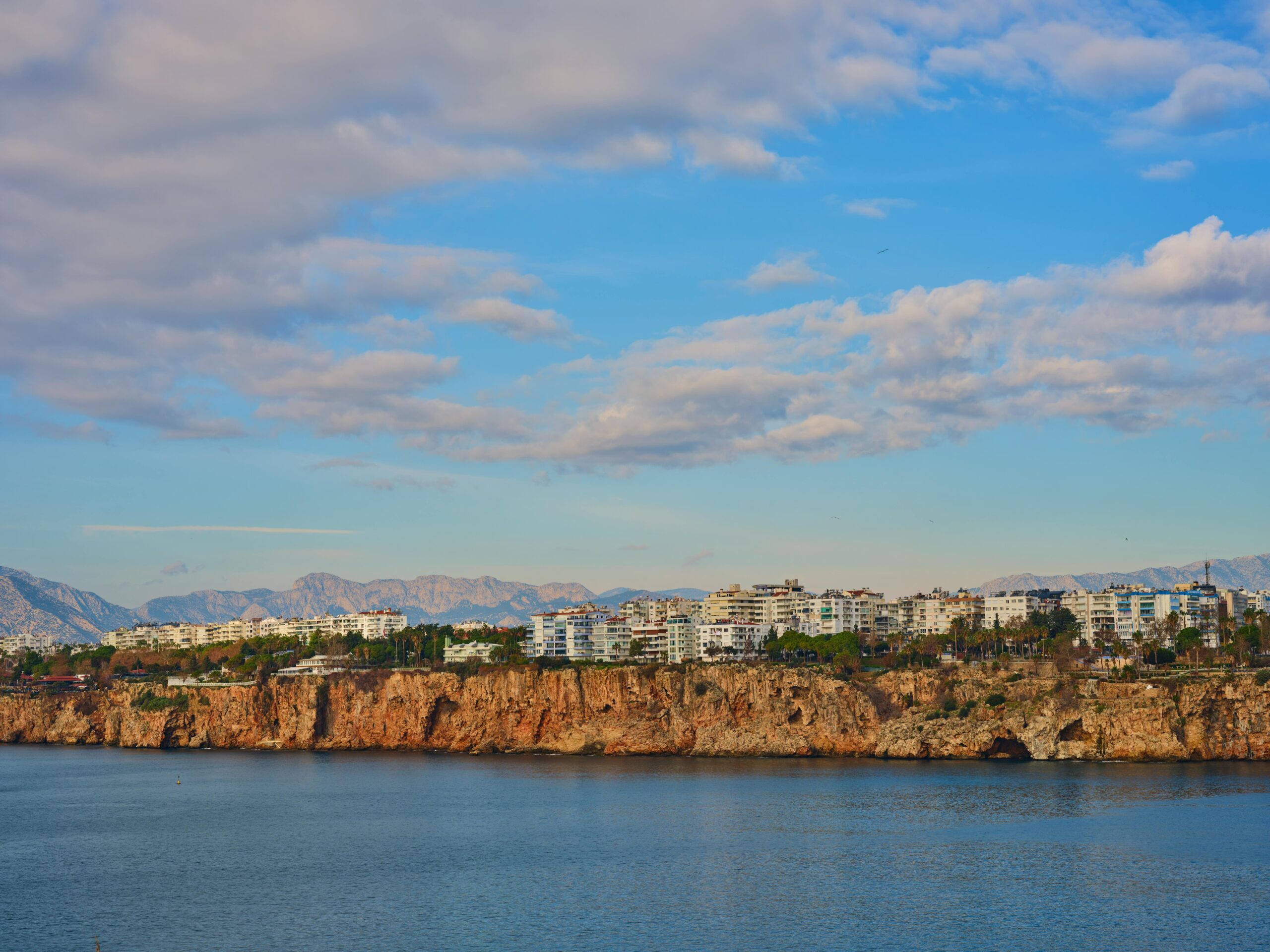 Turcja Antalya apartamenty na klifach - nowoczesne budynki mieszkalne nad Morzem Śródziemnym z górami Taurus w tle, luksusowe nieruchomości z widokiem na morze, inwestycje w kompleksy mieszkaniowe Riwiera Turecka