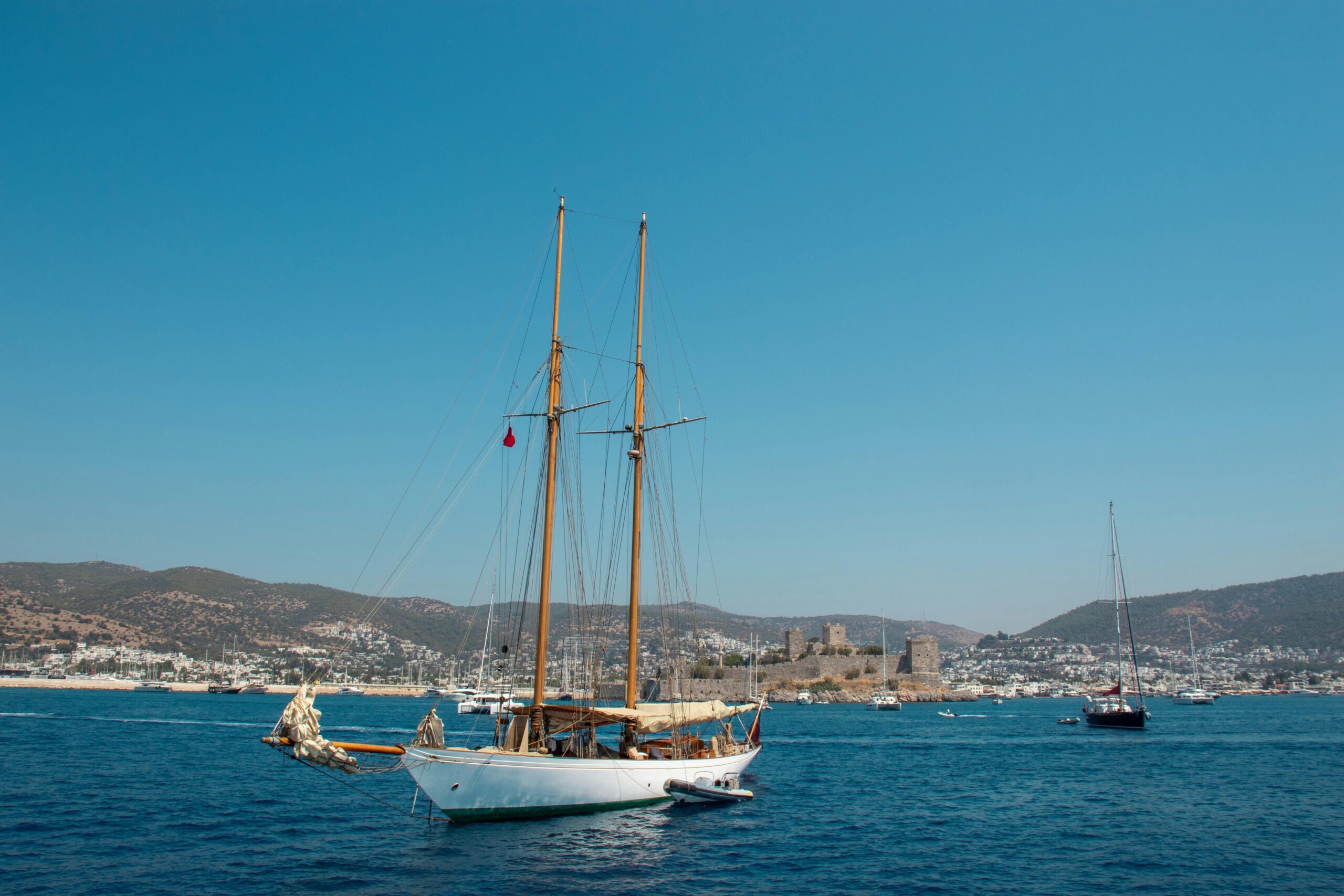 Turcja Bodrum gulet w zatoce - tradycyjna turecka łódź żaglowa przed zamkiem św. Piotra, luksusowe nieruchomości nad morzem z widokiem na historyczną twierdzę, ekskluzywny lifestyle Riwiera Turecka z mariną